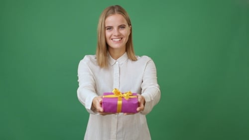Woman Holds Out Gift Box with Ribbon on Green Screen