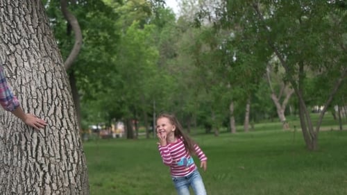 Mother and Daughter Playing Around Tree in Park