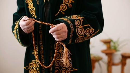 Un vieux mollah en costume national priant avec un chapelet à la main