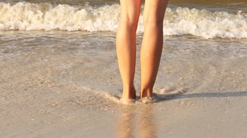 Woman Standing on Sandy Beach with Waves