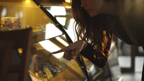 Woman Browsing Dessert Case in a Warm Cafe