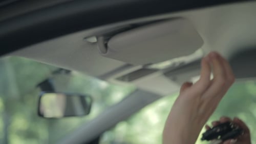 Woman Hiding Ignition Key In Car Sun Visor