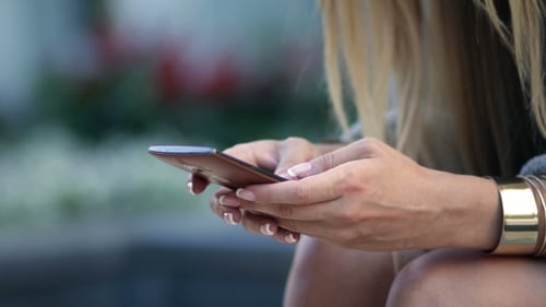 Woman Browsing a Mobile Phone Outdoors