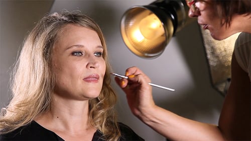 Maskenbildner trägt Make-up auf die Lippen auf