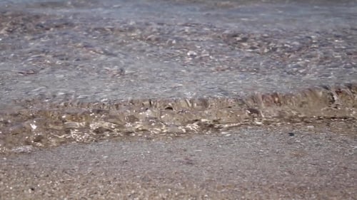 High Angle View Of Foamy Ocean Waves Crashing On To a Pebbled Beach. .