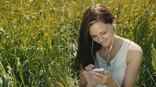Happy Woman Listening To Music And Using Smartphone In The Park