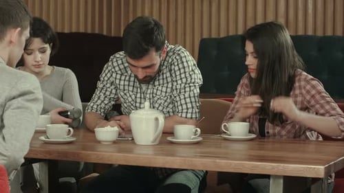 Group of Young People Sitting at a Cafe, Talking and Drinking Tea