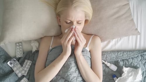 Young Woman is Sick and Lies in Bed Top View