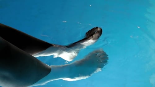 Bare Feet Kicking and Splashing in a Swimming Pool