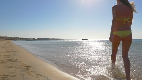 Beautiful Girl Walks Into The Sea At Sunset.