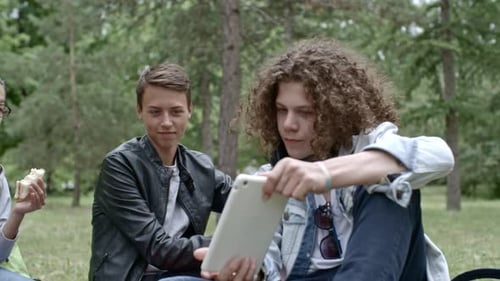 Teens Resting in Park and Using Digital Tablet