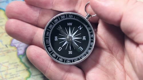 Hand Holding Compass Over Map with Needle Moving