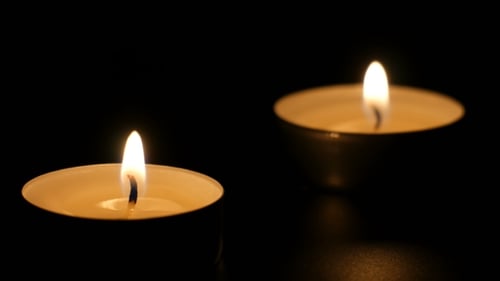 Two Candles Flicker Gently in Dark Room