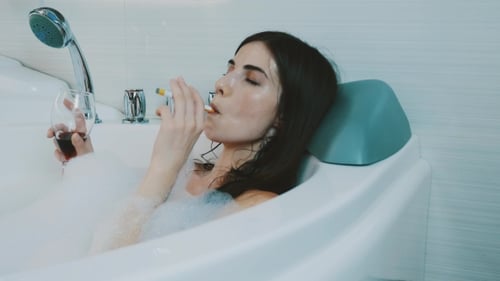 Woman Relaxes in Bubble Bath with Wine