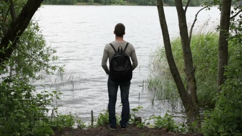 Trauriger Mann steht an einem Ufer eines Flusses