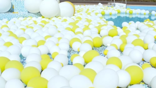 Pool Filled with Yellow and White Balloons