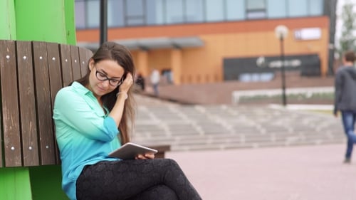 Woman Using Tablet on Bench in Urban Setting