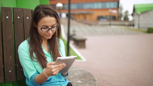 Elegant Young Girl Using The Mini-tablet. Beautiful Student In Glasses