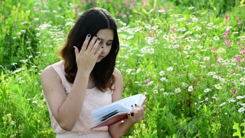 Teenage Girl Reading Book in Meadow of Flowers