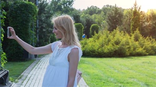 Beautiful Girl Making Selfie Enjoying the Sun in City Park 3