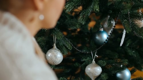 Woman Decorating a Christmas Tree with Ornaments