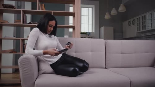 Woman Uses Mobile Device on Couch with Card