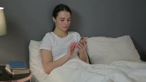 Smartphone Use By Young Woman in Bed