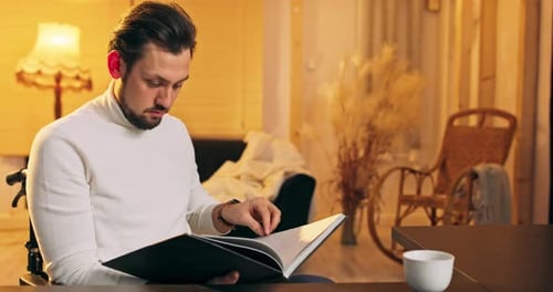 Man Reading Book Indoors in Warm Lighting