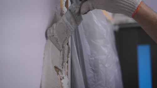 Worker Applying Grey Filler to Wall Edge