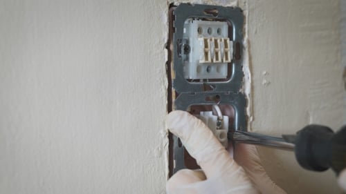 Changing Room Wall Light Switch Installation With a Screwdriver, Electrician Hands.