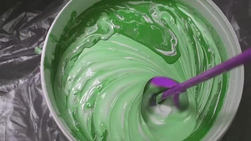 El proceso de mezclar pintura blanca con un tinte de color en el cubo Taladro con una boquilla especial