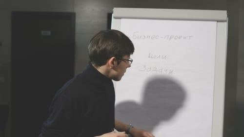 Young Man Presents Business Plan Near Whiteboard
