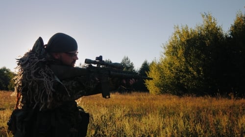 Man in Ghillie Suit with Rifle in Field