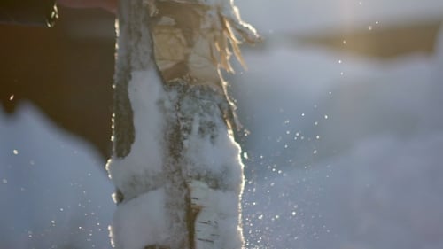 Log being split with axe in winter snow
