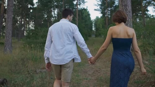 A Pleasant Man With a Beard Leads His Beautiful Wife Or Girl On a Footpath In The Woods.
