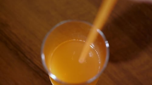 Orange Juice Being Stirred with a Straw