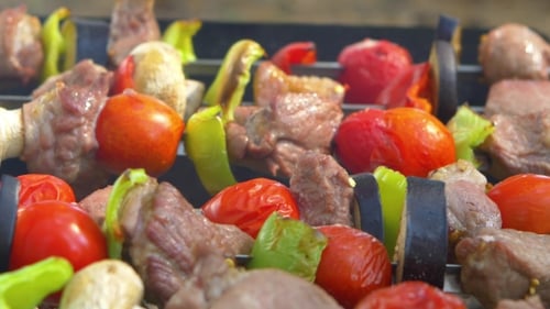 L'homme tourne deux brochettes de brochettes, barbecue mis sur brasero