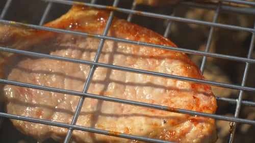 Gegrillte Schweinesteaks über Flammen und Kohlen, Auf dem Kohlenbecken, Cam bewegt sich nach rechts