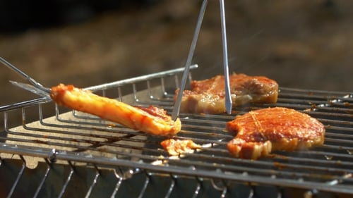 Grilled Pork Steaks Over Flames And Coals, On The Brazier, Taking Away By Blade, Fork