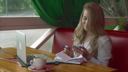 Business Woman In a Cafe Working With Smartphone Laptop And Notebook