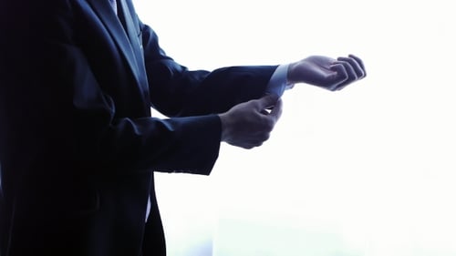 Adult Adjusts Cuffs of Dress Shirt Indoors