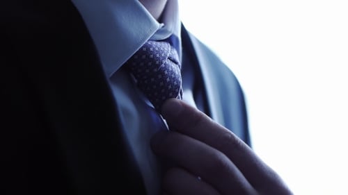 Man Ties a Necktie Knot And Straightens