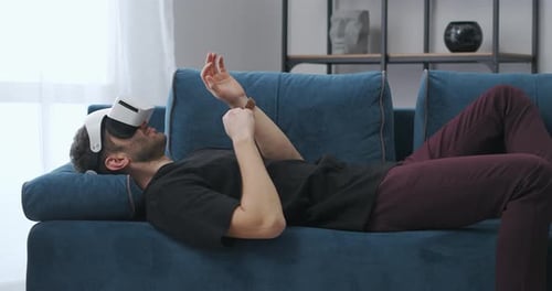 Man Using VR Headset Reclined on Couch at Home