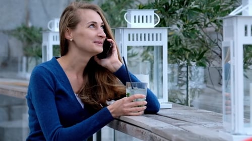 Woman Talking on Phone with Drink Outdoors