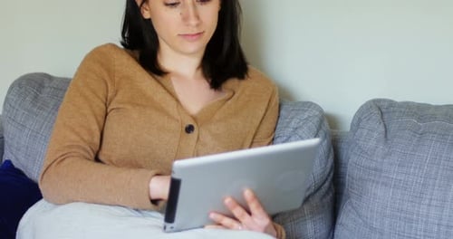 Woman Relaxing on Couch Using Tablet