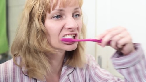 Woman Brushing Teeth in Bathroom Mirror Close Up