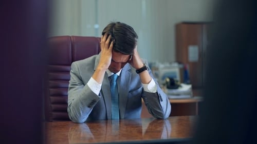 Frustrated Businessman With Head in Hands at Desk