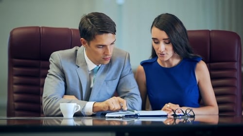 Executives Discussing Notes at Desk in Office