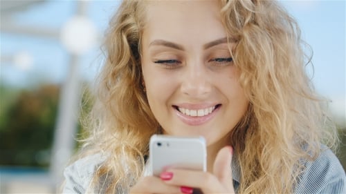 Smiling Woman Using Mobile Phone Outdoors