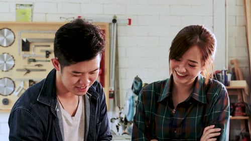 Two Carpenter man and woman are planning construction of built-in furniture in wood workshop